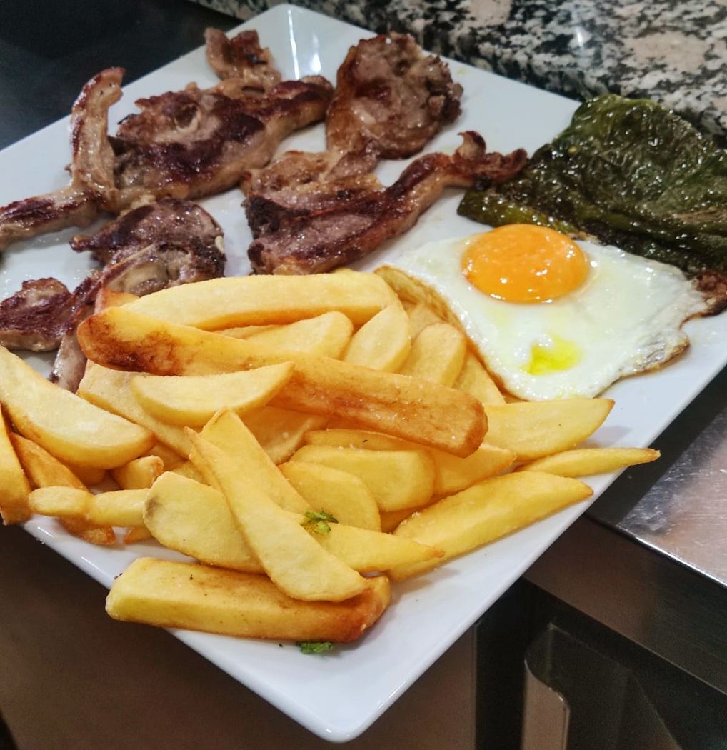 Plato combinado de chuletillas de cordero con huevo frito, patatas y pimientos